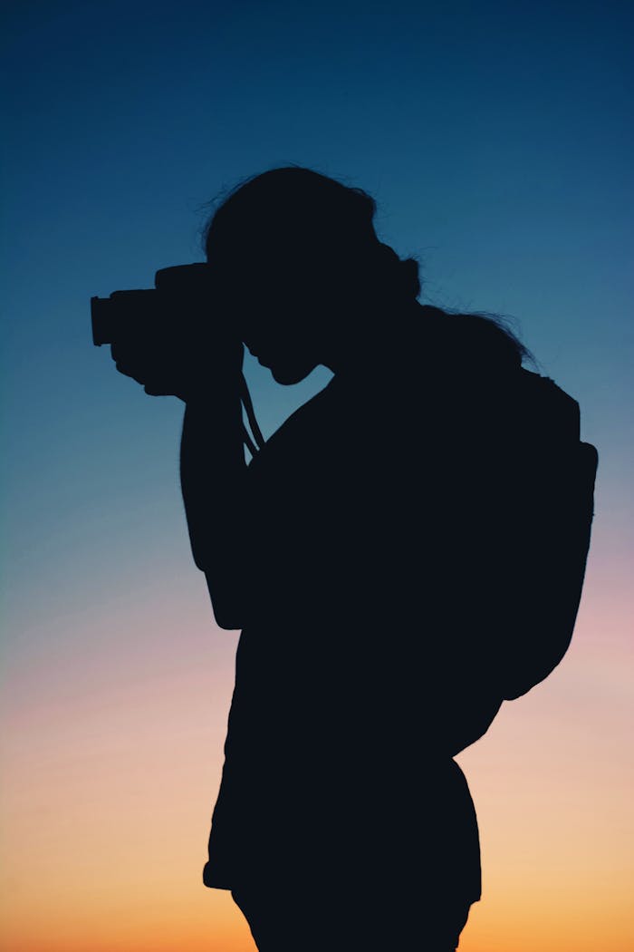 Silhouette of a photographer capturing a stunning sunset, showcasing creativity and passion.